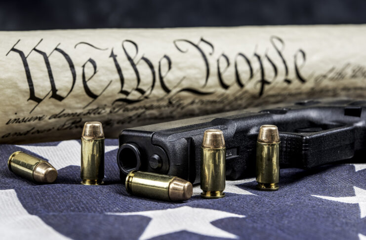 Constitution on an American Flag with a gun and bullets in the foreground