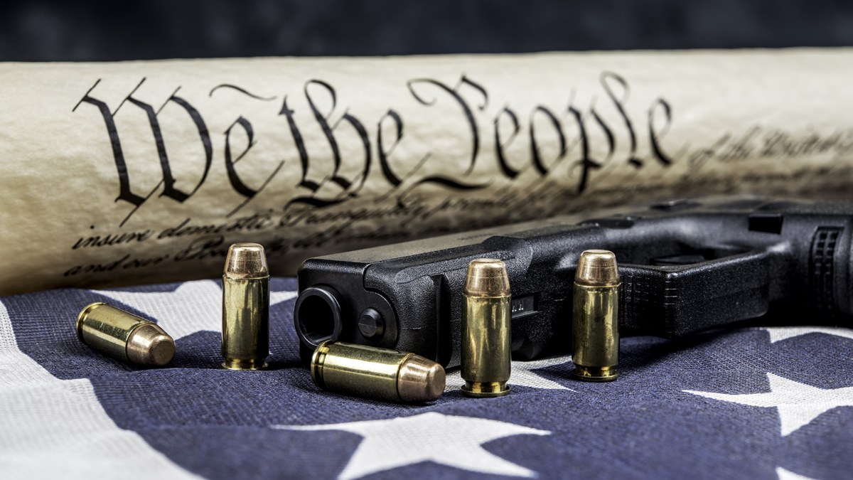 Constitution on an American Flag with a gun and bullets in the foreground